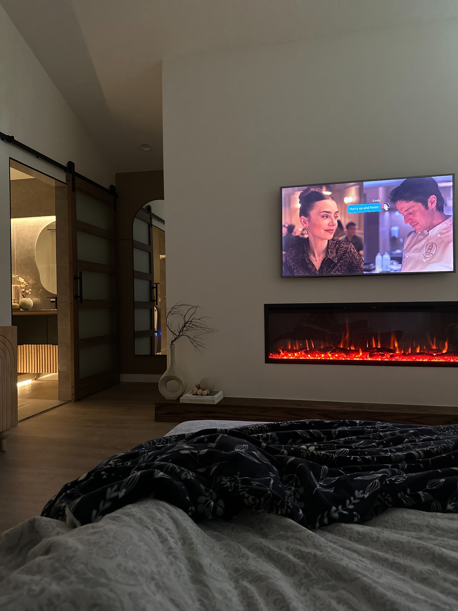 Bedroom after renovation with fireplace, television, and dark sliding doors